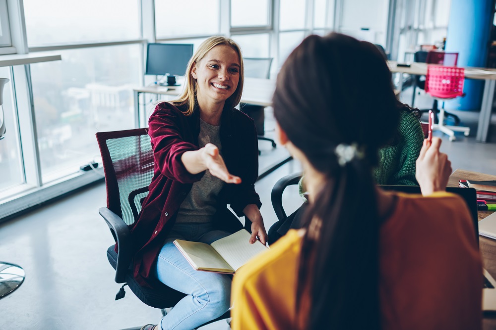 Cheerful,Woman,Pointing,On,Female,Colleague,During,Discussion,About,Business