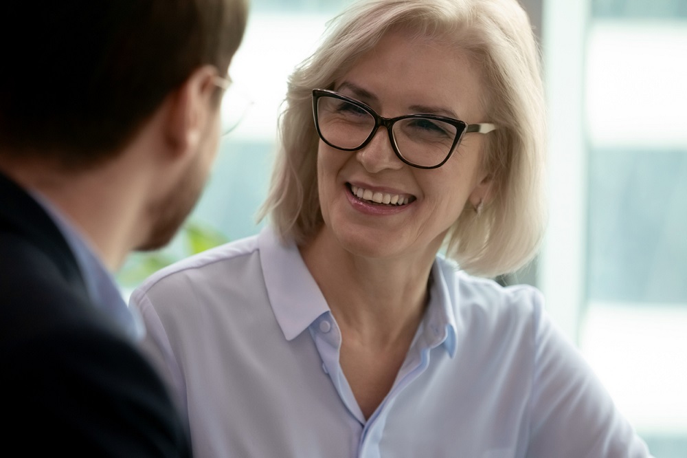 Middle-aged businesswoman talking with partner during meeting in office
