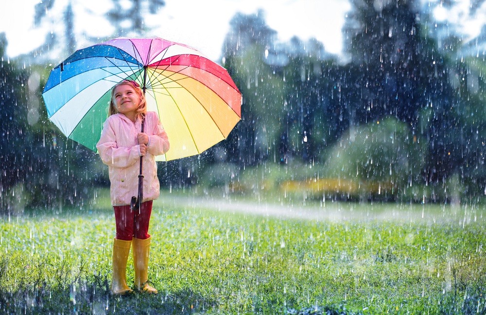 Happy Child With Rainbow Umbrella Under Rain