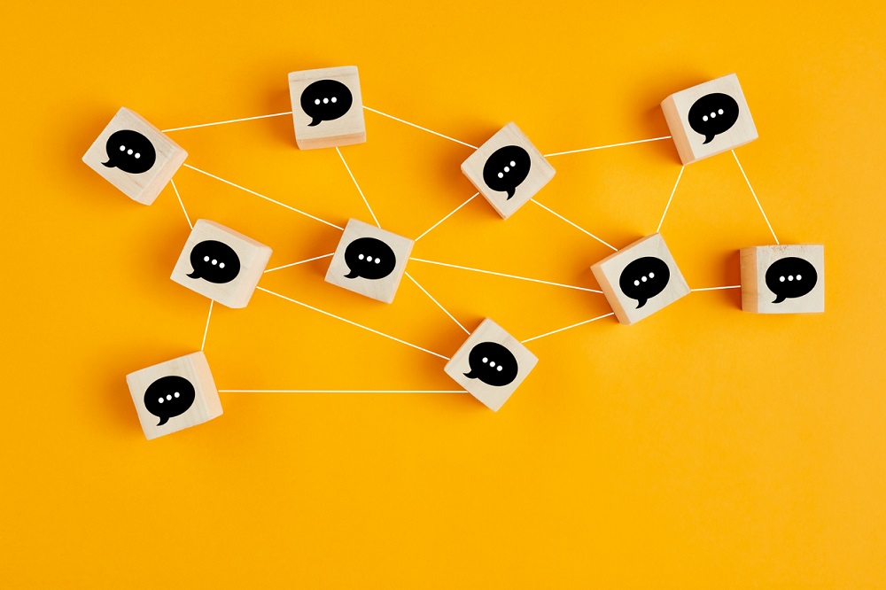 Concept of online communication or social networking. Wooden cubes with speech bubbles linked to each other.