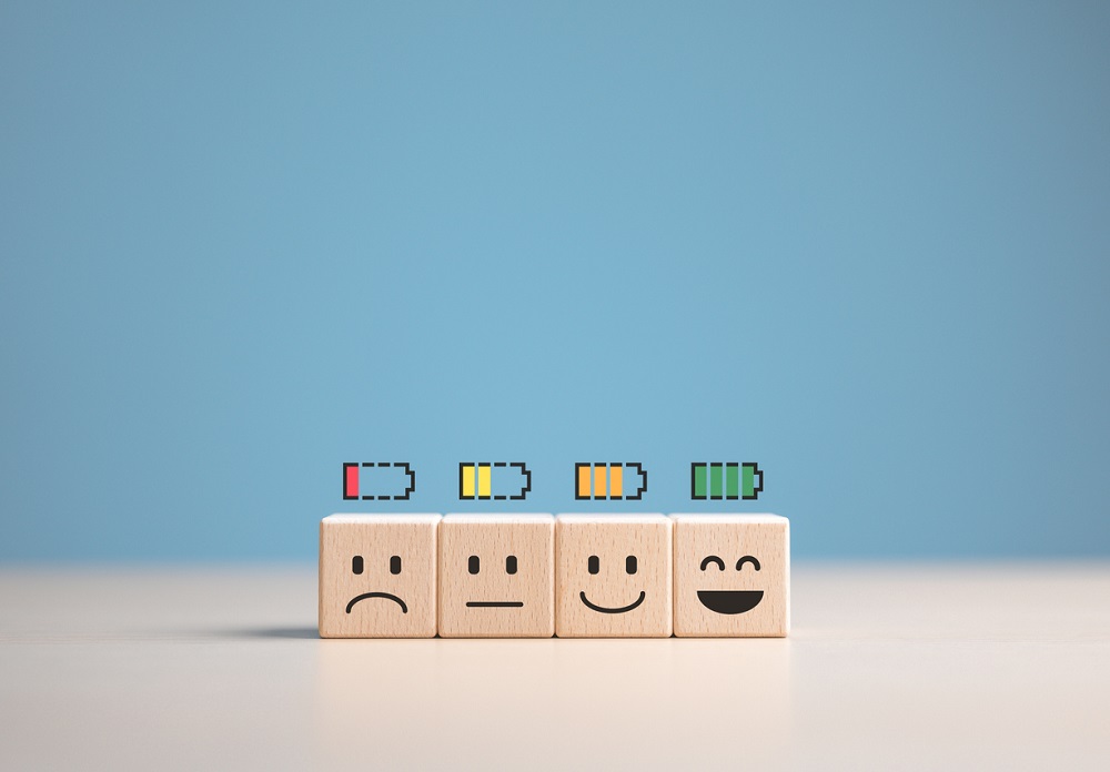 Percent of battery level from sadness to smiley face on wooden cube. Energy to motivate life, Emotional happiness level, World mental health day. Satisfaction, Burnout state, and Positive Thinking.